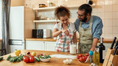 Aşık genç bir çift evde sebzeli pizza yapmak için hamur hazırlıyor. Kadın ve erkek önlük giyiyor, evde birlikte yemek pişiriyorlar. Hobi, yaşam tarzı