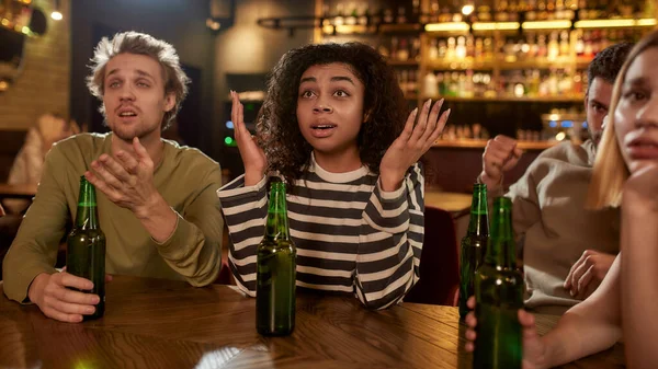 Amigos que se ven decepcionados mientras ven partidos deportivos en la televisión juntos, bebiendo cerveza y animando al equipo en el bar. Gente, ocio, amistad y entretenimiento — Foto de Stock