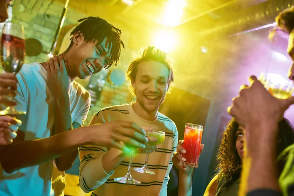 Siente la fiesta. Foto recortada de un grupo de amigos, mujeres jóvenes y hombres brindar mientras se divierten, beber cócteles, pasar tiempo juntos en el club nocturno — Foto de Stock
