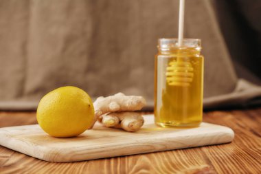 Taze zencefil, limon, bal, kavanozun içinde ahşap tahtada balık, soğuk algınlığı ve grip ilacına hazırlık içeceği.