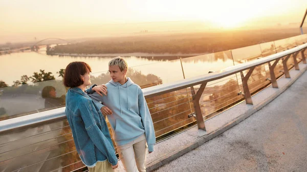 Twee meisjes kijken elkaar aan, staan op de brug, jong lesbisch paar hebben romantisch moment buiten — Stockfoto