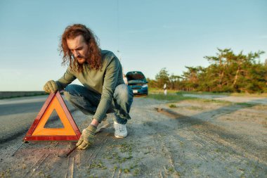 Şoför kırmızı uyarı üçgeni ya da acil durum dur işareti koyuyor yolun kenarına.