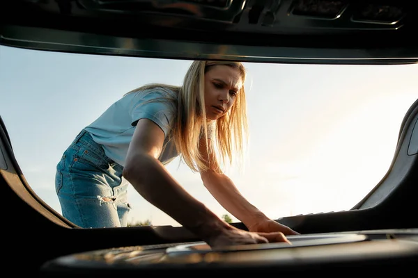 Atractiva joven mujer sacando rueda de repuesto para cambiar el coche roto por su cuenta — Foto de Stock