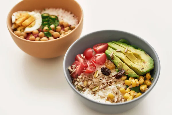 Sağlıklı öğle yemeği fikirleri, iki kase dilimlenmiş sebze ve pirinçle beyaz arka planda izole edilmiş.