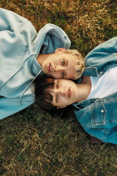 Horní pohled na šťastný lesbický pár dívající se na kameru při ležení na trávě v letním parku. Zamilované ženy spolu tráví čas venku — Stock fotografie