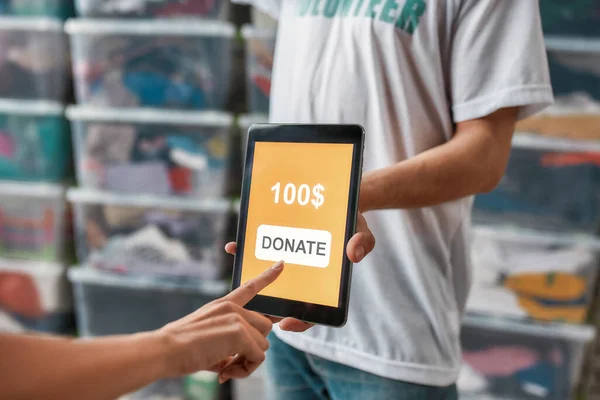 Primer plano de la donación de la mano tocando la pantalla de la tableta PC, voluntarios de publicidad o recomendar la aplicación mientras se trabaja para la caridad — Foto de Stock