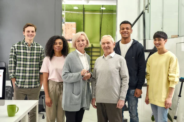 Glücklich vielfältiges Team von Mitarbeitern lächelt in die Kamera, während sie mit älteren weiblichen und männlichen Praktikanten posieren, zusammen im Büro stehen, Altersvielfalt am Arbeitsplatz — Stockfoto