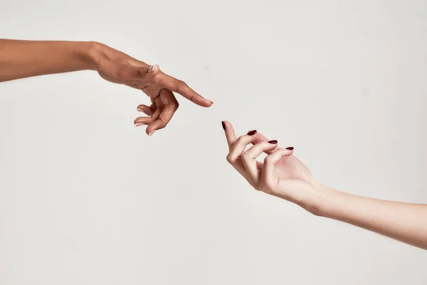 Закрыть две руки различных женщин тянутся друг к другу изолированы на сером фоне — стоковое фото