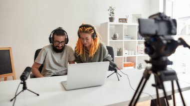 Birkaç blogcu, genç adam ve kadın dizüstü bilgisayarda bir şey izliyorlar, tepki video blogu veya vlog kaydederken gülmemeye çalışıyorlar