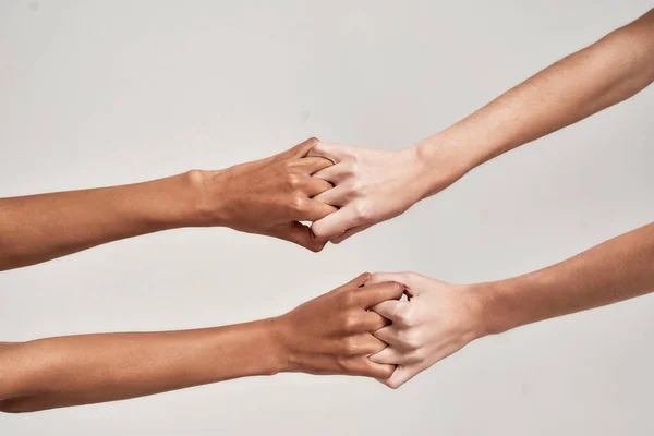 Close up de mãos femininas segurando junto com os dedos cruzados isolado sobre fundo cinza. Diversidade, apoio, conceito de amizade — Fotografia de Stock