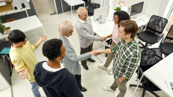 明るく若いチーム挨拶新しい従業員,高齢者と女性,シニアインターン握手で現代オフィスの同僚 — ストック写真