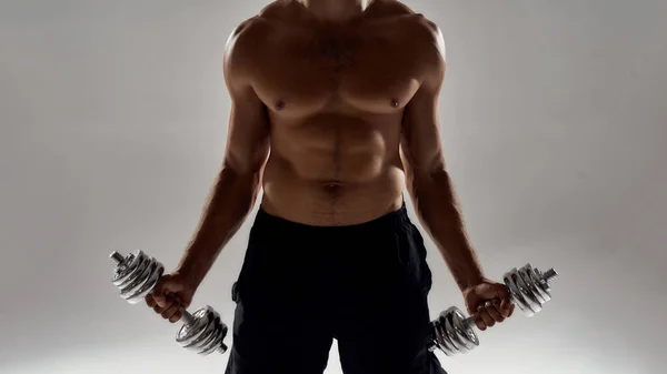 Biceps oefeningen. Gehakt schot van een gespierde blanke man tillen gewichten terwijl staan geïsoleerd over grijze achtergrond — Stockfoto