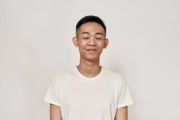 Retrato de un joven asiático con piel problemática e hiperpigmentación en su cara sonriendo con los ojos cerrados aislados sobre fondo blanco. Belleza, cuidado de la piel, concepto de salud — Foto de Stock