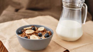 Ev yapımı tahıl gevreğini fındık, bal, yaban mersini ve muzla kaplayıp peçeteyle servis et.