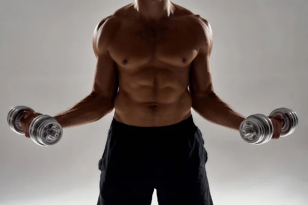 Working hard. Cropped shot of a muscular caucasian man lifting weights while standing isolated over grey background — Stock Photo, Image