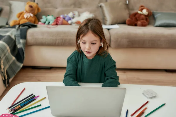 Uma menina gostando de ouvir música sozinha e conversar com seus amigos através de seu laptop durante a educação à distância — Fotografia de Stock