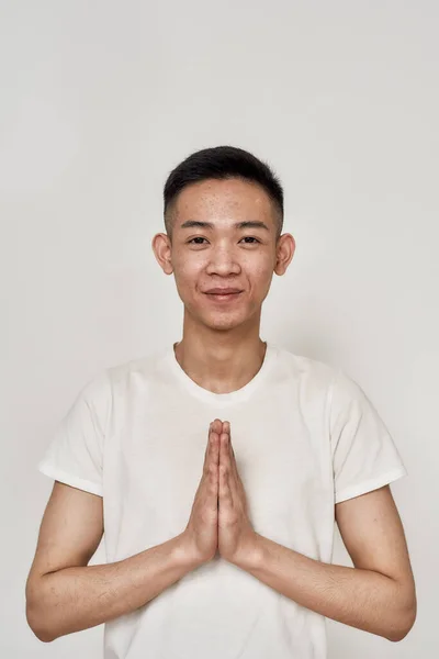 Portrét mladého asijského muže s problematickou pokožkou a hyperpigmentací na tváři při pohledu do kamery, skládající ruce dohromady izolované na bílém pozadí — Stock fotografie