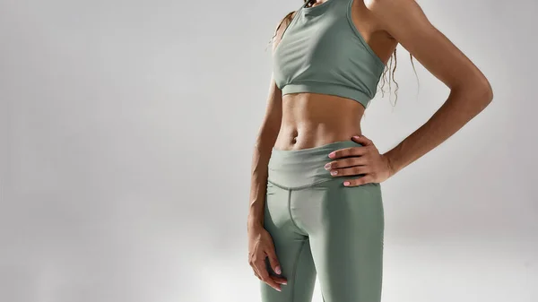 Perfect shape. Cropped shot of slim fitness model in sportswear posing isolated over grey background — Stock Photo, Image