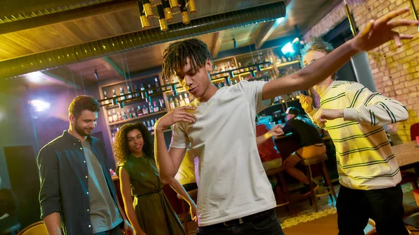 Alegre joven mestizo bailando en la fiesta en el bar. Amigos celebrando, divirtiéndose en el fondo — Foto de Stock