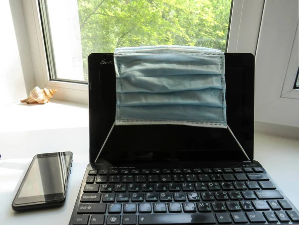 a laptop and a face mask, the work of a freelancer for remote job protection against coronavirus during the epidemic