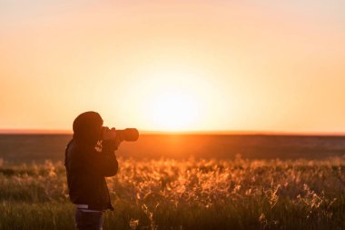 Genç erkek fotoğraf alanında günbatımı vuruyor