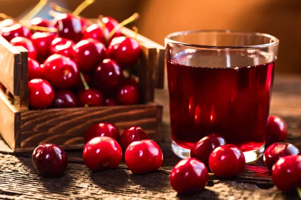 Cerezas frescas en una caja de madera y jugo de cereza —  Fotos de Stock