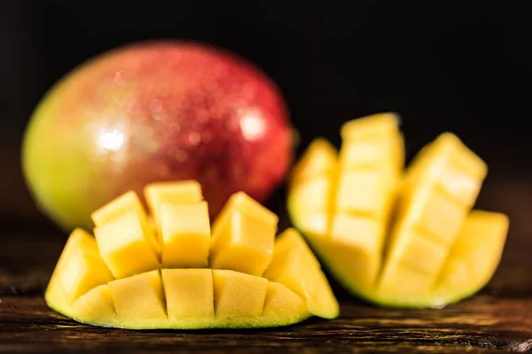 Hela och skär mango på en mörk trä bakgrund — Stockfoto