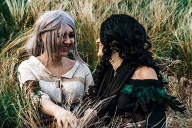 Yennefer ve Cirilla, Wither, birlikte el ele tutuşarak yüksek otların arasında oturan karakterlerinden iki kız kostümü