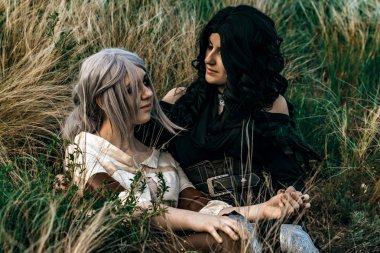 Fantezi cosplay iki güzel oturup birlikte çim