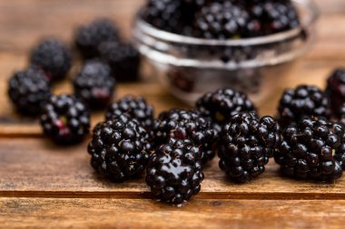 Ahşap masa üzerinde kase taze olgun böğürtlen