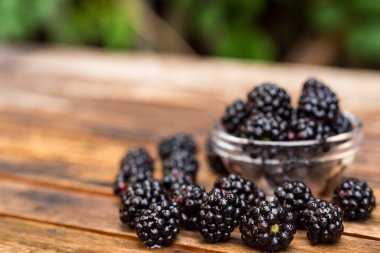 Ahşap masa üzerinde kase taze olgun böğürtlen