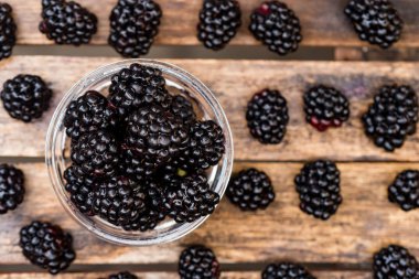 Ahşap masa üzerinde kase taze olgun böğürtlen