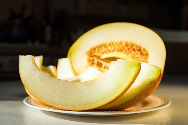 Half melon and melon slices on white plate close