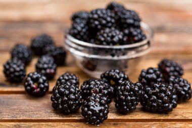 Ahşap masa üzerinde kase taze olgun böğürtlen