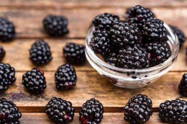 Ahşap masa üzerinde kase taze olgun böğürtlen