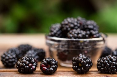 Ahşap masa üzerinde kase taze olgun böğürtlen