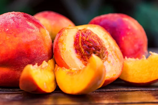 Fresh ripe peaches and slices on wooden table