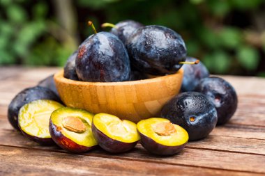 Yakın taze olgun erik ve yarım ahşap kase