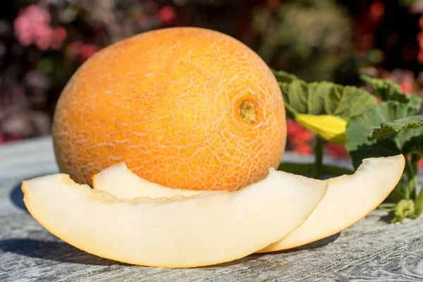 Melon entier et tranché sur table en bois à l'extérieur — Photo