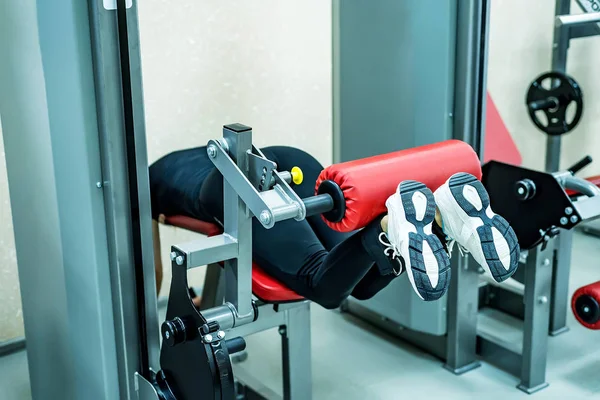 Mujer joven hace ejercicios de piernas en el gimnasio mintiendo —  Fotos de Stock