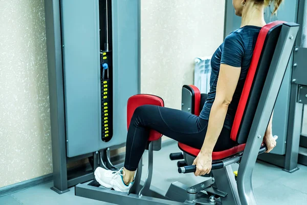 Vista lateral mujer joven hace ejercicios de piernas en el gimnasio — Foto de Stock