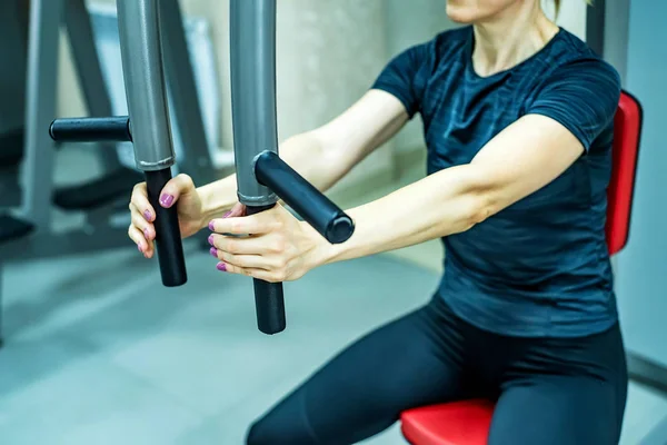 Mujer joven hace ejercicios de brazo en el gimnasio — Foto de Stock