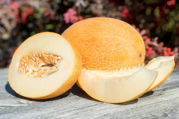 Melon entier et tranché sur table en bois à l'extérieur — Photo