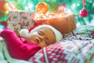 Noel ağacının yanında uyuyan sevimli küçük bebek kız