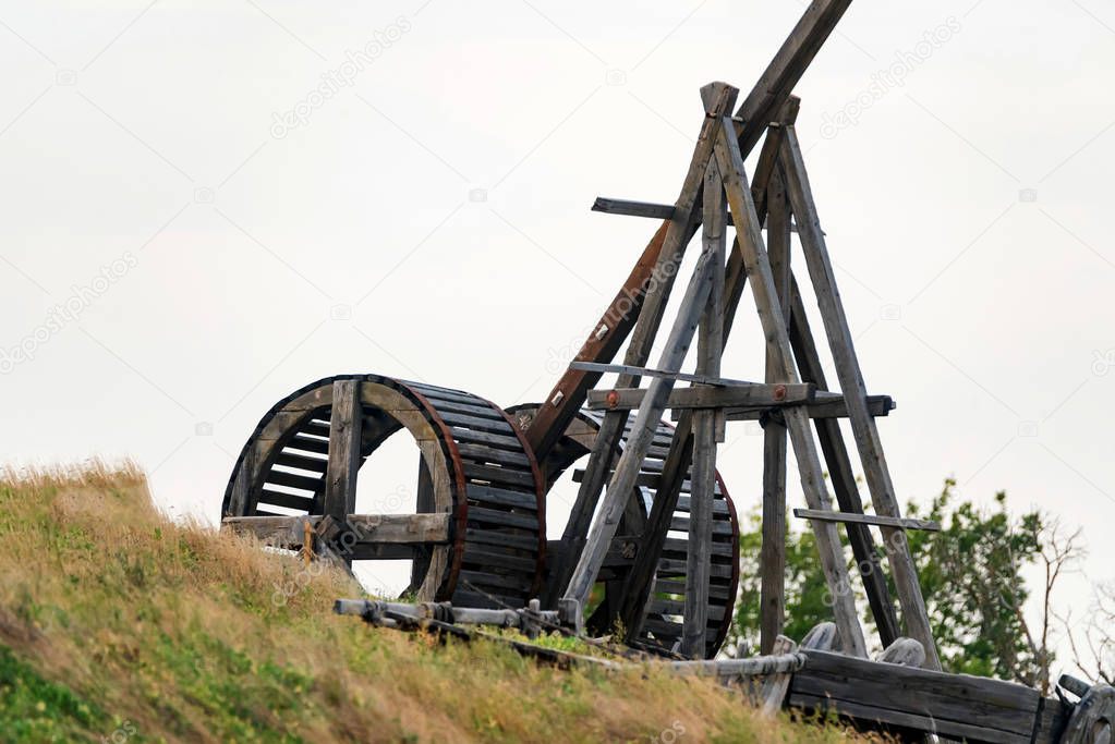 Old wooden catapult against grey sky background