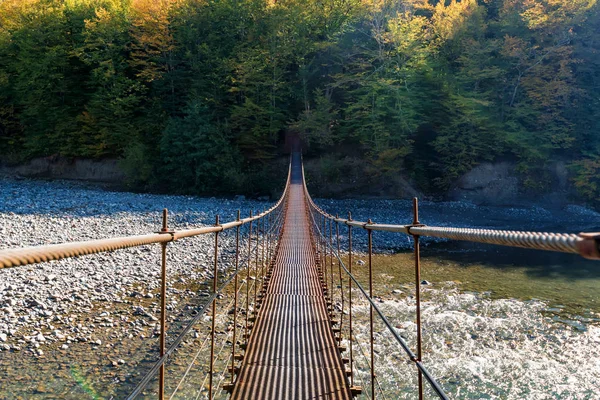 Jembatan logam sempit kaki melintasi sungai di musim gugur — Stok Foto