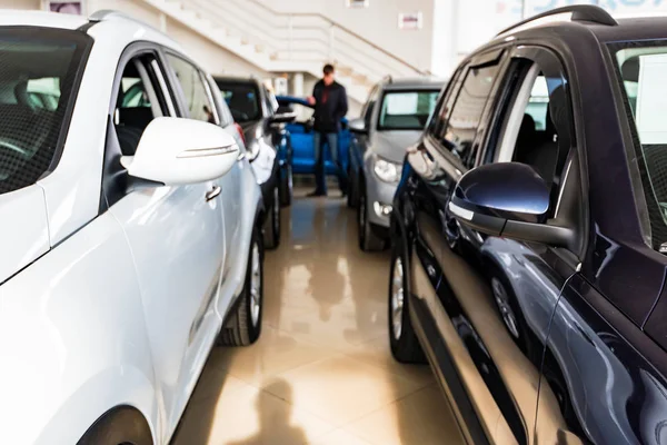 Blurred person looks at new cars at dealer showroom — Stock Photo, Image