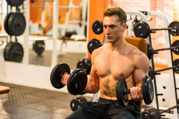 Atraktivní mužský atlet dělá biceps cvičení s činkami — Stock fotografie