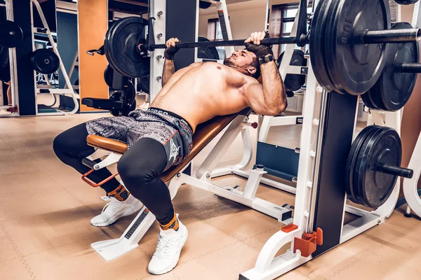 Gespierde bodybuilder bankdrukken training in moderne sportschool — Stockfoto