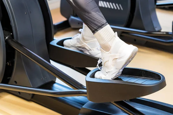 Close up female feet on elliptical trainer in gym — Stock Photo, Image